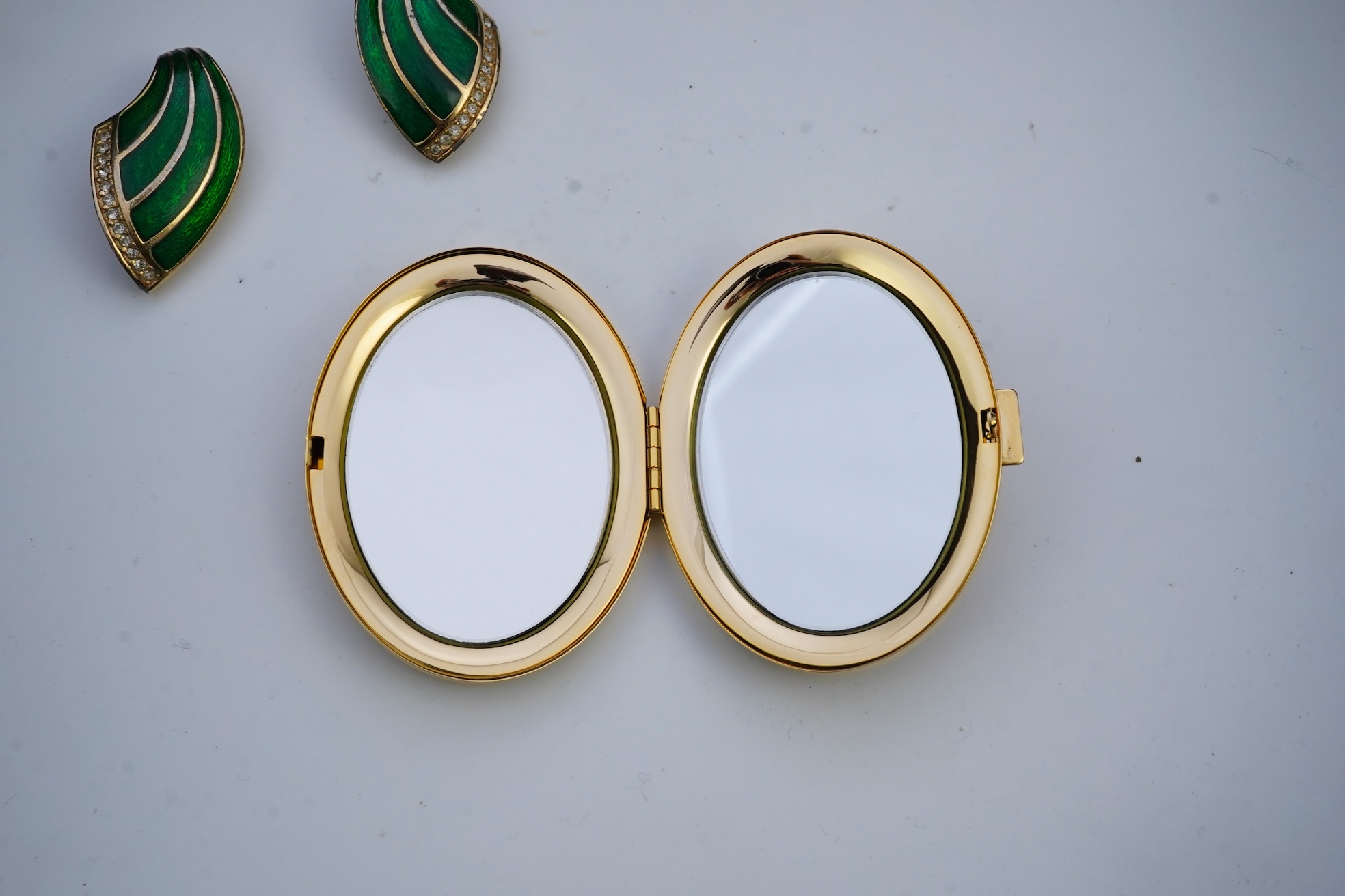 A pair of Christian Dior vintage earrings and compact mirror.